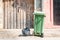 One single green garbage can and black plastic junk bag on the street in the city waiting for dumper truck to collect in front of