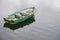 One single green rustic wooden boat alone in sea water