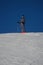 one skier stands on the mountain against the cloudless blue sky