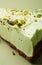 One slice of pistachio cheesecake on sight green background