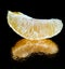 one slice of tangerine on a black background reflection fruit food macro texture