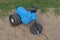 One small blue black plastic childrens tricycle stands on gray sand