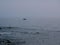 One small fishing boat heading out on the foggy ocean at dawn