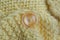One small plastic brown button on a yellow woolen knitted fabric