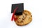 One smart cookie Idiom and a symbol for intelligent concept with close up on a cookie wearing a graduation cap isolated on white