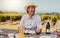 One smiling mature mixed race woman enjoying a wine tasting day on a farm. Happy hispanic woman wearing a hat while