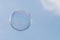One soap bubble floating against light blue sky.  