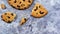 One soft freshly baked chocolate chip cookie with crumbs and chunks on a gray marble kitchen countertop. American traditional