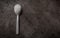 One spoon full of refined sugar on a dark kitchen counter