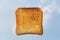 One square ruddy pieces of bread for toast on the blue sky with white clouds background