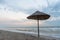 One straw umbrella on the sea beach