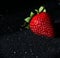 One strawberry on a black background with sequins. Red berry