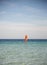 One surfer under a red sail against a sea and sky