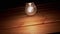 One Swinging Hanging Glowing Incandescent Light Bulb on a Wooden Background