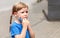 One tired, unhappy and worried anxious little girl, child taking off a protective anti viral face mask, young school kid portrait