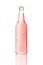 One transparent glass bottle. Pink drink in bottle with condensed water drops isolated on white