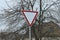 One triangular road sign give way with gray branches