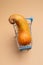 One ugly curved pear in small blue supermarket cart on beige background. Vertical orientation.