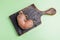 One ugly potato on  burned wooden kitchen board on green background.