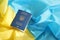 One Ukrainian biometrical passport on folded waving flag of Ukraine country