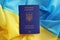 One Ukrainian biometrical passport on folded waving flag of Ukraine country