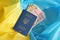 One Ukrainian biometrical passport and UAH hryvnia bills on folded waving flag of Ukraine
