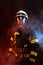 One uniformed firefighter posing against black background covered in smoke