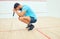 One unknown athletic squash player crouching and feeling sad and stressed after playing game on court. Fit active mixed