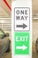 One way and exit signs on pillar in parking garage with parked cars to either side - close-up an selective focus