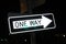 One Way street sign pointing to the right at night with nighttime reflection