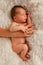 One week old baby on white blanket and female hand