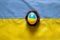 One white chicken egg with a painted flag of Ukraine in a straw basket lies on the flag of Ukraine, culture and holidays