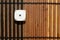 One white plastic dice on brown wooden board background. Six sides cube with black dots. Number 1