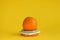 One whole orange on colorful stand on yellow background. Copy space.