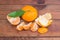 One whole and peeled mandarin orange on dark wooden surface