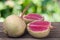 One whole and sliced watermelon radish on a wooden table with blurred garden background