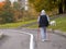 One woman goes Nordic walking with a white dog. Sports walk on a cloudy autumn morning in a city park