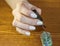 One woman hand with white manicure hold brush with clear varnish