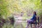 One woman relaxing, unwinding while seated at natural park bench in Fall season, Spain, 2019.