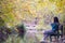 One woman relaxing, unwinding while seated at natural park bench in Fall season, Spain, 2019.