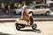 One woman riding a vespa scooter in the city street traffic in motion blur