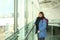 One woman tourist with a backpack in a bright building of an airport lounge waiting at the window and looking at the street,