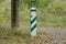 One wooden striped pillar stands in the grass