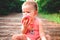 One year old baby sitting in a forest feeding in a paleo way, biting an apple