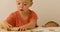 One-year-old child watching how three-year-old playing with puzzle