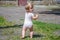 A one-year-old girl stamps her bare feet on small stones, increasing immunity in nature in children. A little girl walks barefoot