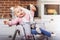 One year toddler girl sits on baby high chair with feeding bottle in her hand.