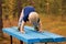 One year toddler makes yoga on the bench in the autumn park. Downward Facing Dog pose. Adho Mukha Svanasana