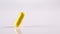 One yellow medication falling against white background