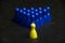 One yellow pawn and group of blue pawns on a table